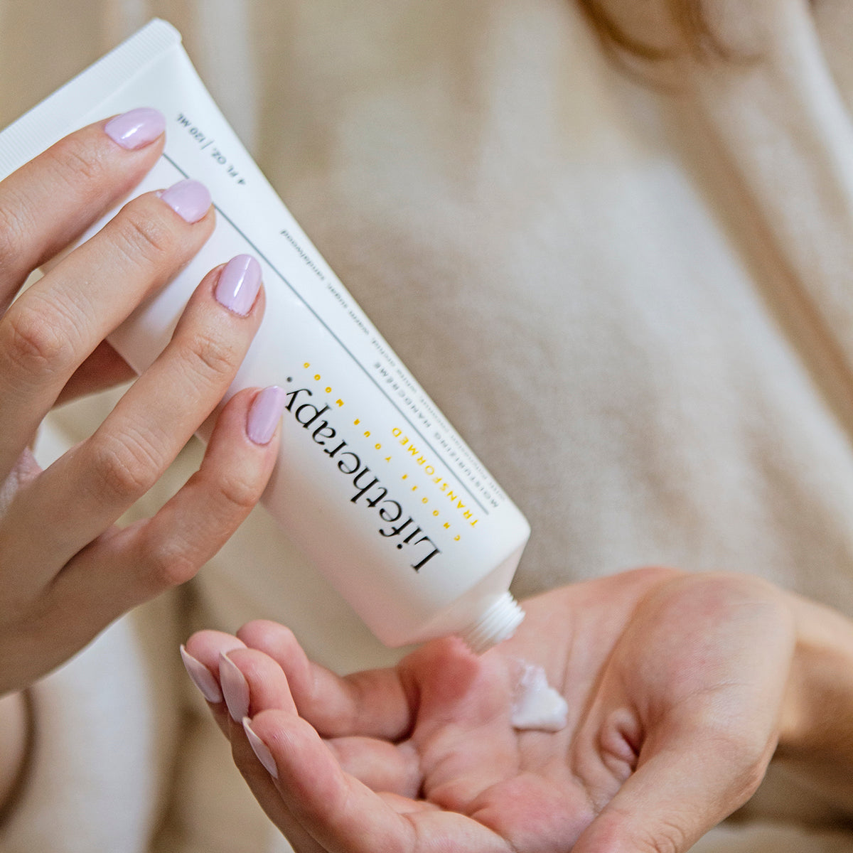 Woman applying Transformed Lifetherapy hand cream with Polynesian coconut and white orchid for deep skin repair.